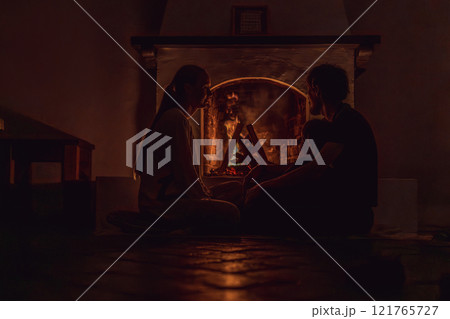 Family bonding by the fireplace during cozy winter evening. Warm and peaceful family moment indoors. Togetherness, love, and relaxation concept. A warm and inviting scene featuring a lit fireplace 121765727