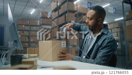 Postal service: African American logistics specialist scans parcel, uses computer 121766055