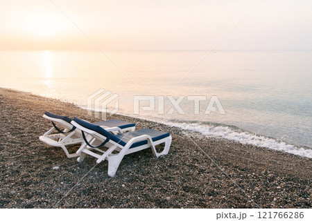 Two plastic sun beds on the sea beach at sunrise. Summer vacation concept. 121766286