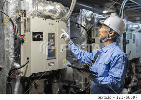 ビルの空調設備（吸収冷温水器）を点検をする作業員　ビルメンテナンススタッフ　イメージ　 121766697