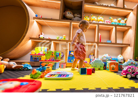 Toddler enjoying a playful and creative indoor environment filled with toys, games, and engaging activities for learning and fun 121767821