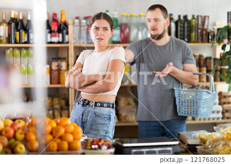 Husband calms his wife down after an argument in grocery supermarket, apologizing Husband calms his wife down after an argument in grocery supermarket, apologizing 121768025