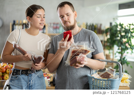 In trading floor, spouses buyers inspects hamon and dried sausage, scan QR code on product label 121768125