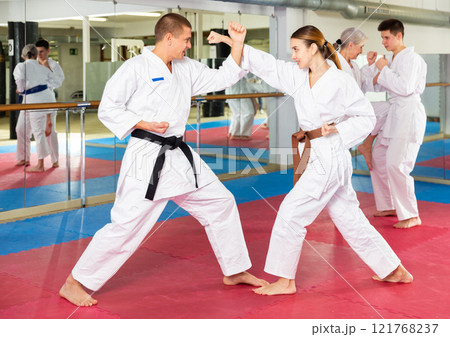 Man and woman in kimono sparring during group karate training 121768237