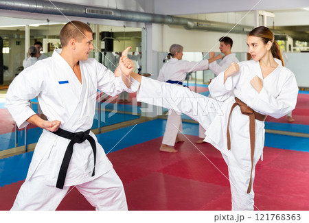 Woman and man in kimono and belts fighting during karate training 121768363