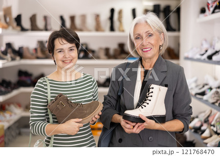Adult and elderly women choosing boots in store 121768470