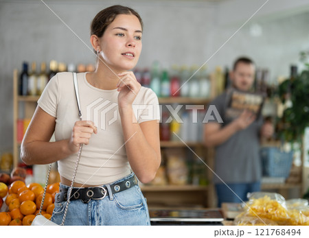 Grocery shopping at supermarket - girl chooses somtething in grocery supermarket 121768494