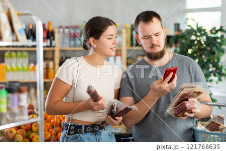 Couple man and woman scanning qr code for dried sausages and jamon 121768635