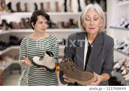 Adult and elderly women choosing boots in store 121768649
