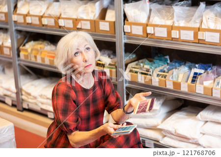 Elderly woman chooses shade of paint from palette Elderly woman chooses shade of paint from palette 121768706