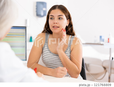 Young woman consulting with faceless beautician on anti-aging treatments in cosmetology clinic 121768809