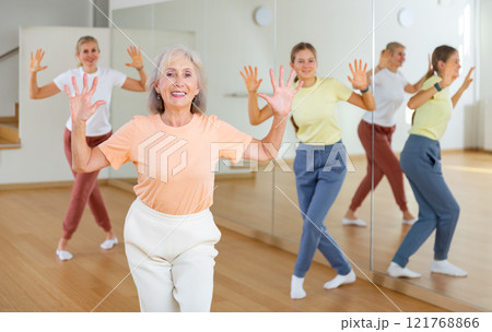Elderly woman learning aerobic dance with her younger relatives 121768866