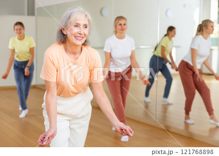 Elderly woman dancing jazz during group training Elderly woman dancing jazz during group training 121768898