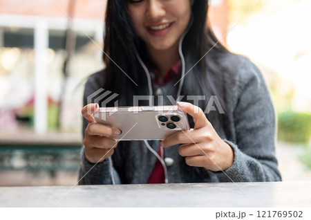 A cropped image of a happy Asian woman enjoys watching a movie and playing a mobile game outdoor. 121769502