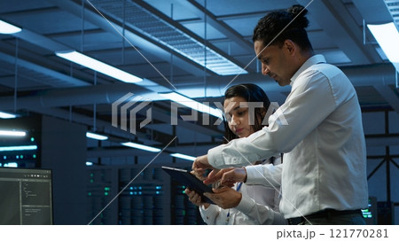 Team of technicians working on tablets in data center used for managing gear energy consumption. Teamworking colleagues using devices in workspace used for automation in server farm Team of technicians working on tablets in data center used for managing gear energy consumption. Teamworking colleagues using devices in workspace used for automation in server farm 121770281