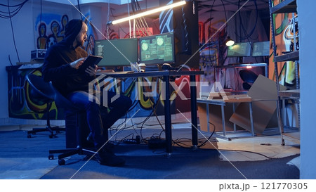 Man arriving in underground bunker, using it to mask his location while committing international espionage. Spy using tablet and computer systems to steal governmental secrets Man arriving in underground bunker, using it to mask his location while committing international espionage. Spy using tablet and computer systems to steal governmental secrets 121770305