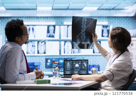 Medical specialist showing x ray diagnostic report and blood test analysis to a patient at consultation in cabinet, providing advice and treatment on health insurance. Scan medical results. Medical specialist showing x ray diagnostic report and blood test analysis to a patient at consultation in cabinet, providing advice and treatment on health insurance. Scan medical results. 121770538