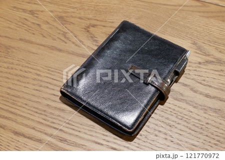 アンティークテーブルに置かれた黒い本革の手帳 121770972