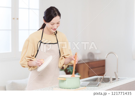 パソコンを見て料理する女性 パソコンを見て料理する女性 121771435