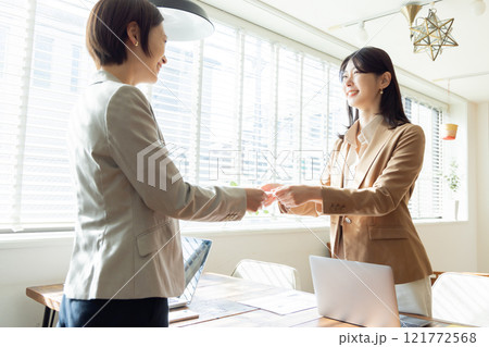 名刺交換するカジュアルな服装の女性 名刺交換するカジュアルな服装の女性 121772568