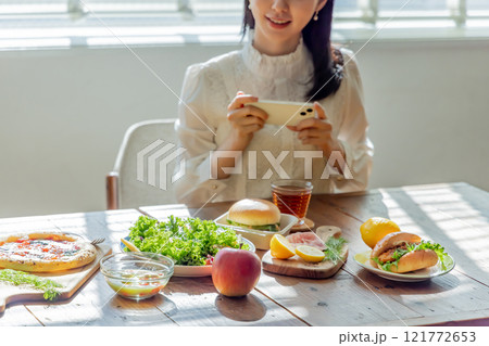 カフェで食事をしながらスマホを使う若い女性 121772653