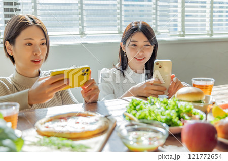 食卓の料理写真を撮る女性 121772654