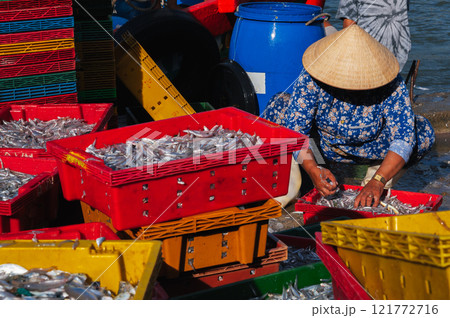 Vietnamese women in conical hats prepare fish for sale at local market Vietnamese women in conical hats prepare fish for sale at local market 121772716