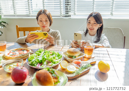 食卓の料理写真を撮る女性 121772732