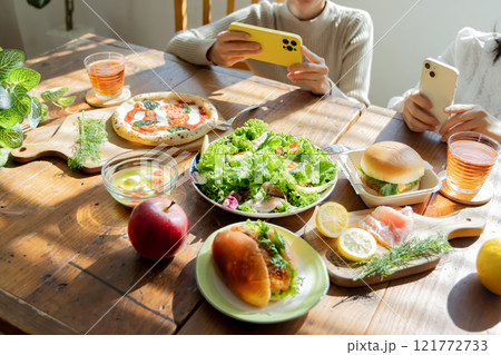 食卓の料理写真を撮る女性 121772733
