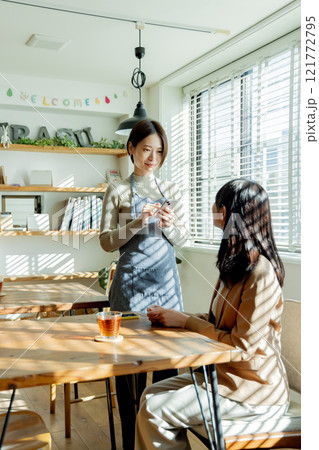 カフェでオーダーを聞く女性スタッフ カフェでオーダーを聞く女性スタッフ 121772795