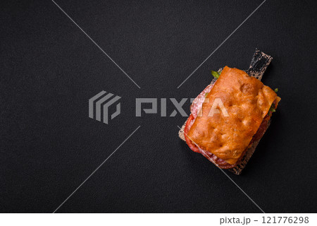 Focaccia with salami, cheese, tomatoes, arugula, salt, spices and herbs Focaccia with salami, cheese, tomatoes, arugula, salt, spices and herbs 121776298