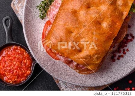 Focaccia with salami, cheese, tomatoes, arugula, salt, spices and herbs Focaccia with salami, cheese, tomatoes, arugula, salt, spices and herbs 121776312