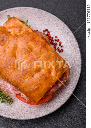 Focaccia with salami, cheese, tomatoes, arugula, salt, spices and herbs Focaccia with salami, cheese, tomatoes, arugula, salt, spices and herbs 121776316