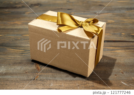 Brown gift box tied with a golden ribbon on a wooden table 121777246