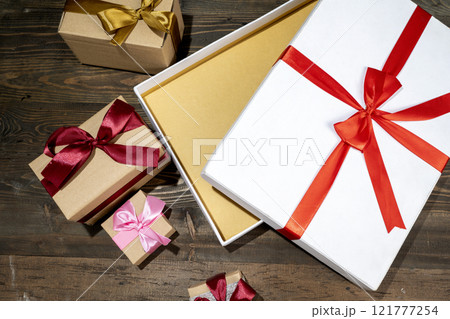Opening a white gift box tied with a red ribbon on a wooden table Opening a white gift box tied with a red ribbon on a wooden table 121777254