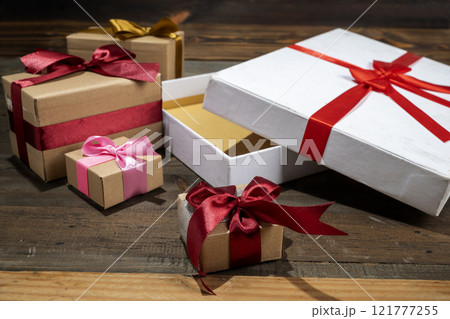 Opening a white gift box tied with a red ribbon on a wooden table Opening a white gift box tied with a red ribbon on a wooden table 121777255