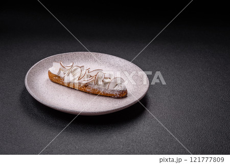 Sweet eclair with custard decorated with coconut slices Sweet eclair with custard decorated with coconut slices 121777809