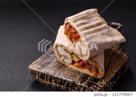 Roll with pita, meat, tomatoes, cheese, sauce, salt and spices 121778067
