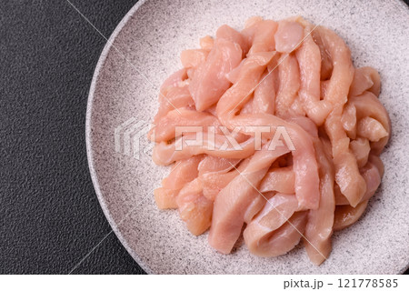 Raw chicken fillet cut into strips with spices and herbs Raw chicken fillet cut into strips with spices and herbs 121778585