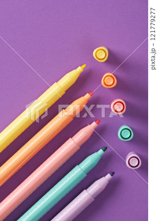 Multicolored pastel markers on a purple backdrop. Stationery background. 121779277