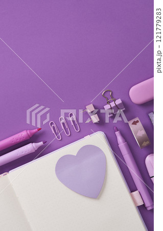Minimalistic pastel stationery flatlay with open notepad, heart shaped sticker and stationery - felt tip pens, pen, paper clips, clipboards and eraser on a lilac background. Place for your text. Minimalistic pastel stationery flatlay with open notepad, heart shaped sticker and stationery - felt tip pens, pen, paper clips, clipboards and eraser on a lilac background. Place for your text. 121779283