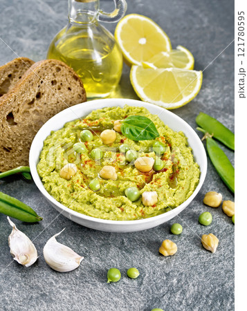Hummus from green peas in bowl with bread on table Hummus from green peas in bowl with bread on table 121780595