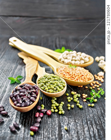 Lentils with chickpeas and beans in spoons on black board 121780604