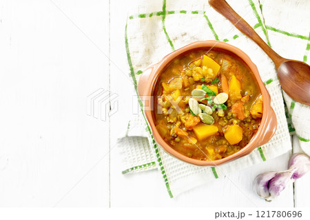 Soup-curry with pumpkin and lentils in bowl on white board top Soup-curry with pumpkin and lentils in bowl on white board top 121780696