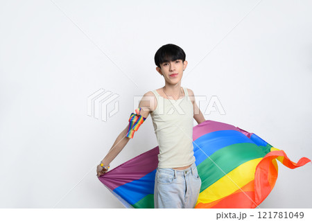 Cute asian man holding rainbow pride flag on white background. LGBTQ pride and equality concept 121781049
