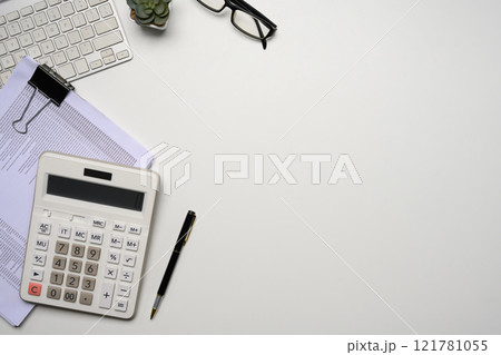 Top view of a tidy workspace with calculator, keyboard, glasses and a stack of documents Top view of a tidy workspace with calculator, keyboard, glasses and a stack of documents 121781055