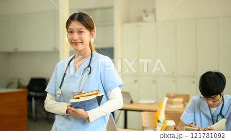 Medical student holding textbooks and smiling confidently at camera Medical student holding textbooks and smiling confidently at camera 121781092