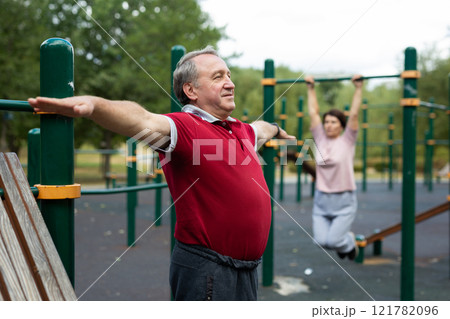 Elderly man doing gymnastics on an outdoor sports ground Elderly man doing gymnastics on an outdoor sports ground 121782096