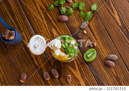 homemade yogurt with kiwi, honey and nuts in a glass on a wooden table homemade yogurt with kiwi, honey and nuts in a glass on a wooden table 121782318