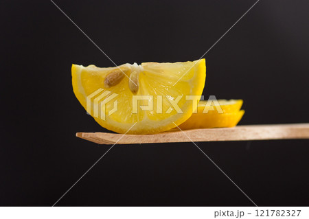 slice of fresh juicy lemon on wooden spatula isolated on black background 121782327